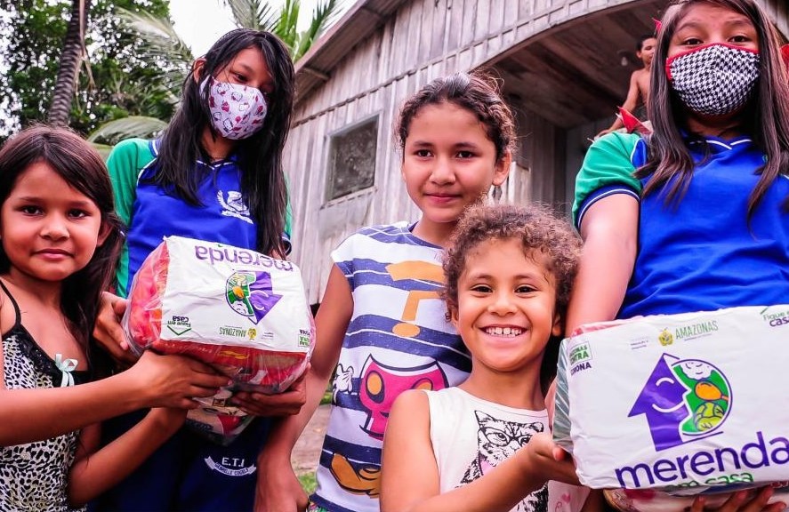 Schoolchildren in Amazonas holding Merenda em Casa food kits